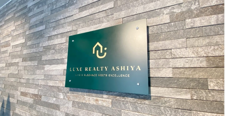 石壁に掲げられたリュクスリアルティ芦屋の緑色の看板