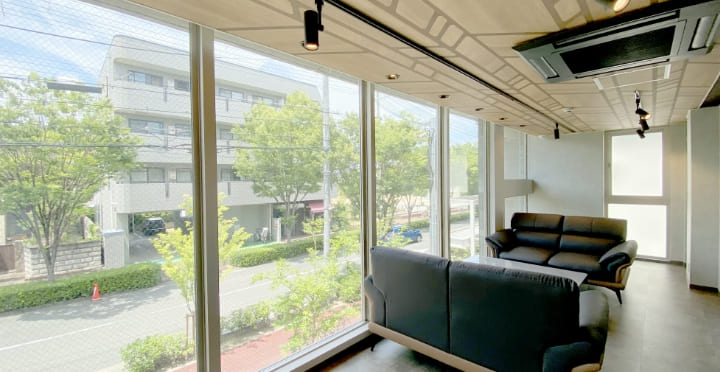 大きな窓から自然光が差し込む応接スペースとモダンなソファ